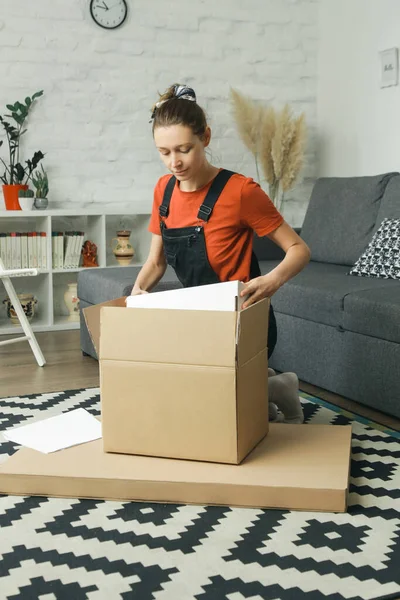 Kafkasyalı bir kadın karton kutuyu açıyor. Adresi teslim etmiş.