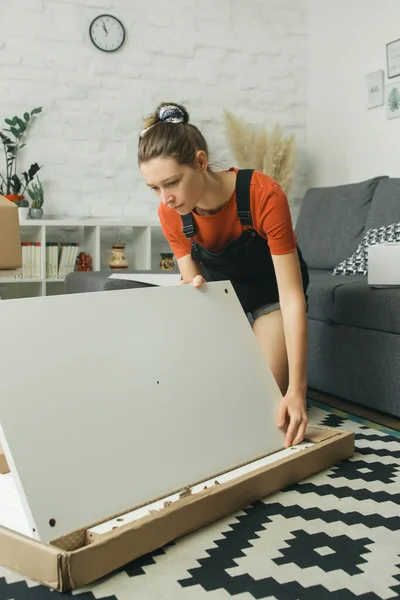 Caucasian woman at home assembling furniture by herself