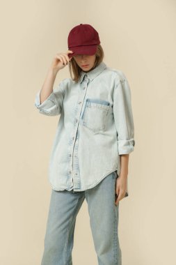 Modern gündelik kıyafet, mavi kot pantolon, beyaz atlet, kot ceket, kırmızı beysbol şapkası.