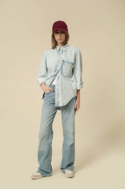 Modern gündelik kıyafet, mavi kot pantolon, beyaz atlet, kot ceket, kırmızı beysbol şapkası.