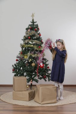 Şirin küçük bir kız Noel ağacını kış tatili için süslüyor.