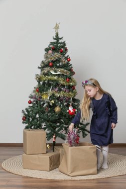 Şirin küçük bir kız Noel ağacını kış tatili için süslüyor.