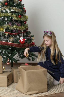 Şirin küçük bir kız Noel ağacını kış tatili için süslüyor.