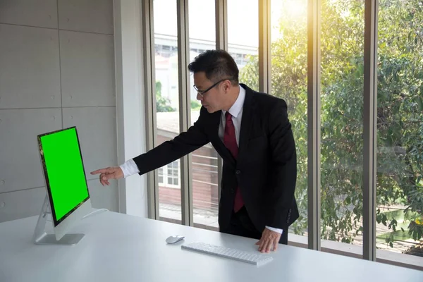 Handsome businessman point the finger at a blank screen computer