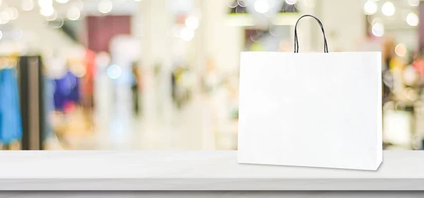 Saco de compras de papel branco em pé na mesa de mármore branco sobre bl — Fotografia de Stock