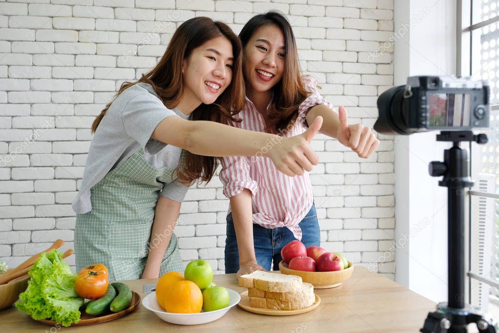 Two young asian woman food bloggers talking while recording vide