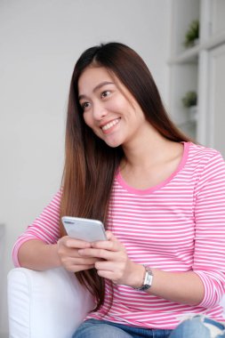 Genç asyalı kadın gülümseyen, mutlu ve rela ile akıllı telefon kullanarak