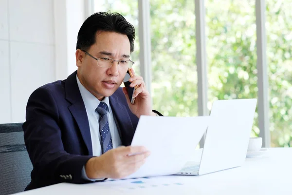 Azjatycki biznesmen czytania dokumentów rozmawiać telefon i pracy z — Zdjęcie stockowe