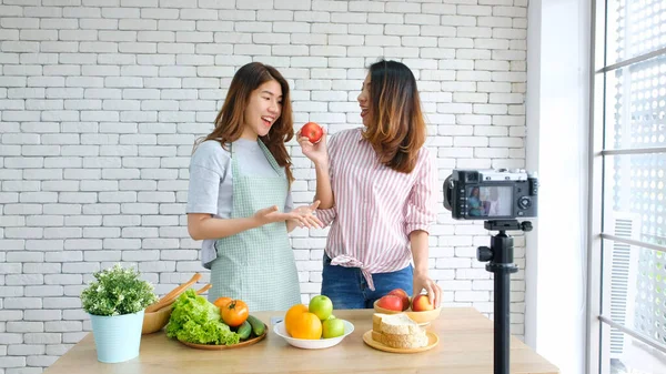 İki genç Asyalı kadın yemek blogcusu videoyu mutlu bir an, vlog konsepti, insanlar ve teknoloji iletişimi ile kaydederken konuşuyor.