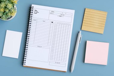 Boş defter kağıdı ve mavi masa arkaplanındaki yapışkan not defteri, üst görünüm, düz yatış