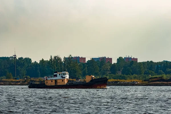 Old tug ship moving to the cargo terminal. Industrial service