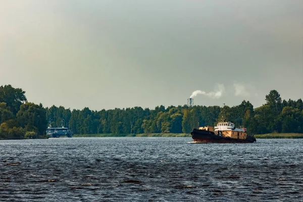 Old tug ship moving to the cargo terminal. Industrial service