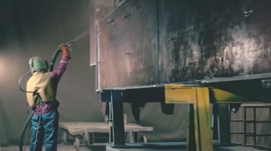 Adam metal yüzey Kumlama cihazının silah bir metal konstrüksiyon fabrikada tarafından temizler. Shotblaster bir süreç içinde