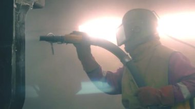 Adam metal yüzey Kumlama cihazının silah bir metal konstrüksiyon fabrikada tarafından temizler. Shotblaster bir süreç içinde