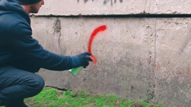 Street Hooligan escribiendo en la pared usando una lata de pintura en aerosol — Vídeos de Stock