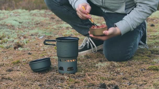 Vandrare kokar pasta med konserverad gryta i en skog — Stockvideo