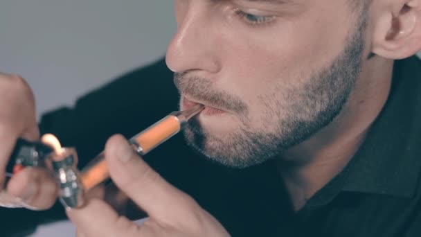 Молодой человек курит травку с помощью трубы в помещении — стоковое видео