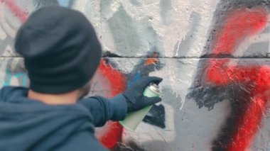 Grafiti çizen genç adam sprey boya kutusu kullanıyor.