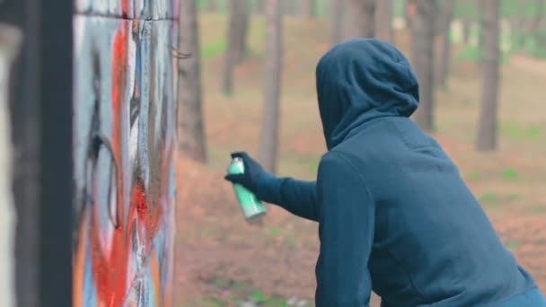 Молодой парень рисует граффити с помощью баллончика с краской — стоковое видео