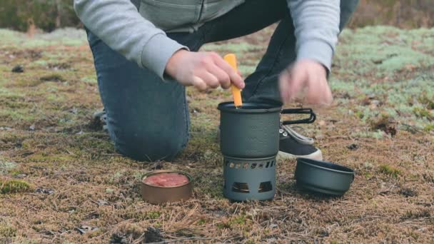 Turista vaří těstoviny s konzervovaným gulášem v lese — Stock video