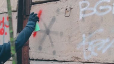 Sokak serserisi duvarda sprey boya kutusu kullanıyor.