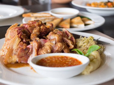 Bir tabakta sebze ve baharat soslu çıtır çıtır kızarmış domuz bacak yerleştirilir