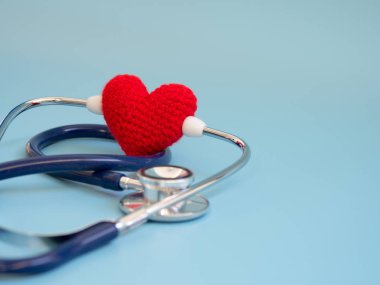 Kırmızı kalp mavi arka plan üzerinde koyu mavi stetoskop kullanarak. Sevgi ve bakım hasta tarafından kalp kavramı. Kopya alanı metin ve içeriği için