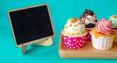 Metniniz için boş yazı tahtası ve kopya alanı ile ev yapımı kek ve renkli. Cupcake yeşil zemin üzerine ahşap tepsi.