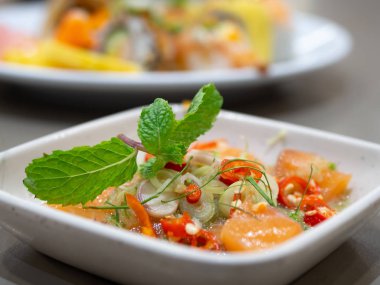 Baharatlı Tay otlar beyaz bir tabak içinde özel soslu somon salatası. Somon kişniş ile tepesinde. Japanese Restaurant.