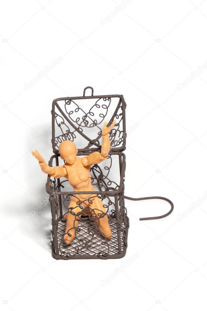 Action figure sitting and hold two hands above the head in open steel cage on isolate background, Concept of tolerance in comfort zone do not dare to change and Fear of change