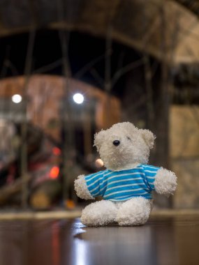 Beyaz ahşap masa şöminenin önünde oturan mavi gömlek giymiş ayıcık metin için yer kopyalayın.