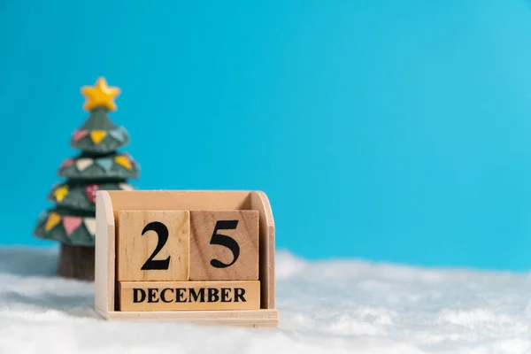 Christmas tree backside wooden block calendar set on the Christmas date 25 december on white wool and blue background. Copy space for text or content. Concept of 25/12 merry christmas.