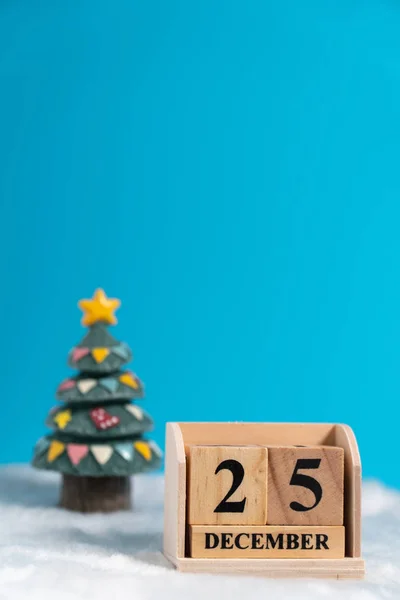 Christmas tree backside wooden block calendar set on the Christmas date 25 december on white wool and blue background. Copy space for text or content. Concept of 25/12 merry christmas.