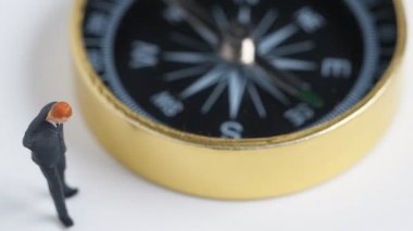 Minyatür resim döndürme tarafında koyu mavi takımı ayakta işadamı altın pusula. Nasıl iş başarısı için yol bulmak için kavramı