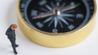 Minyatür resim döndürme tarafında koyu mavi takımı ayakta işadamı altın pusula. Nasıl iş başarısı için yol bulmak için kavramı