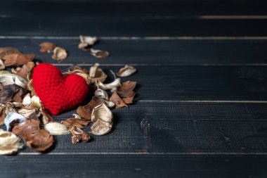 el Kırmızı kalp iplik kurutulmuş yaprakları ile yapılan ve siyah ahşap masanın üzerine yerleştirilen çiçek yaptı. sevgi ve Sevgililer günü kavramı. Kopya alanı metin ve içerik için