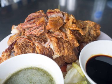 Bir tabakta sebze ve baharat soslu çıtır çıtır kızarmış domuz bacak yerleştirilir