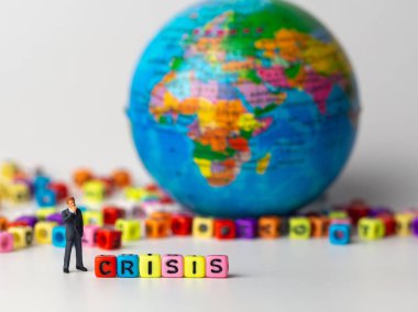 Minyatür resim işadamı kriz alfabesinin renkli koyu mavi takımı ayakta arka ve arka plan ve düşünme kriz dünya gelecek.