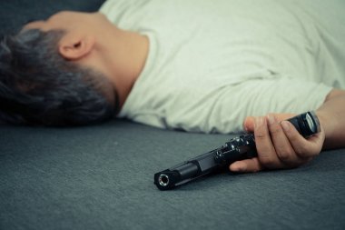 Orta yaşlı Asyalı adam 40 yaşında elinde silah tutmak ve evinde kanepeüzerinde yatıyordu. İş ve çevre toplumdan stres alan insanların durumunu simüle etmek