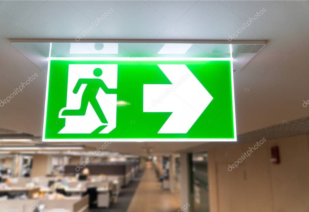 Green fire escape sign hang on the ceiling in the office.