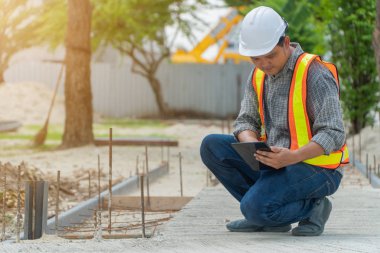 Mühendislik, kask takan ve elinde tabletler olan, parkta koridorun yapısını kontrol etmek için oturuyor