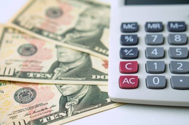 Beyaz arka plan daki 10 dolarlık banknotlar hesap makinesi. Gelir ve Giderlerin Hesaplanması Kavramı