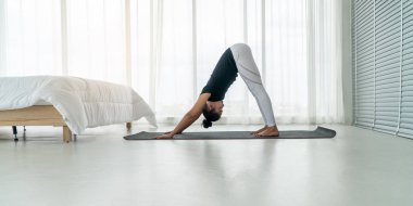 Orta yaşlı kadınlar aşağı bakan köpek yoga yapıyor sabah yatak odasında yoga ile meditasyon poz, adho mukha svanasana poz. Sabah egzersiz ve gevşeme kavramı.
