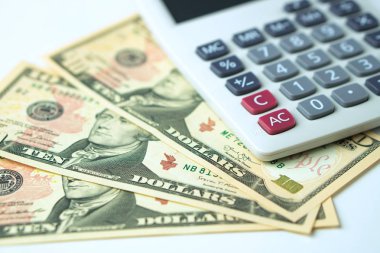 Beyaz arka plan daki 10 dolarlık banknotlar hesap makinesi. Gelir ve Giderlerin Hesaplanması Kavramı