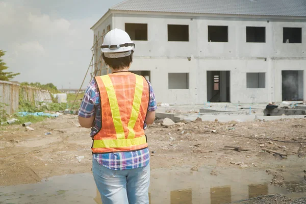 Portrait of Asian woman construction engineer worker with helmet on head using tablet while standing on construction site. building site place on background. Construction concept