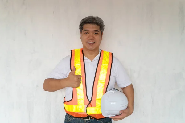 Asian professional engineer workering in house construction site for inspection of the cottage under construction and lift the thumb up.