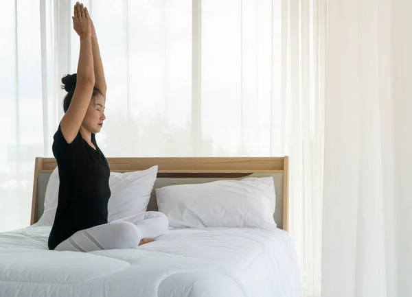 Middle aged women doing yoga in bedroom at the morning, adho mukha svanasana pose. Concept of exercise and relaxation in the morning.