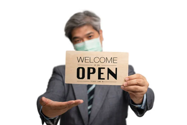 アジアのビジネスマンは 隔離された背景に医療マスクを着用し 歓迎を保持我々はオープンサインです ビジネスやお店のコンセプトは 状況がリラックスし始めた後に開く必要があります — ストック写真