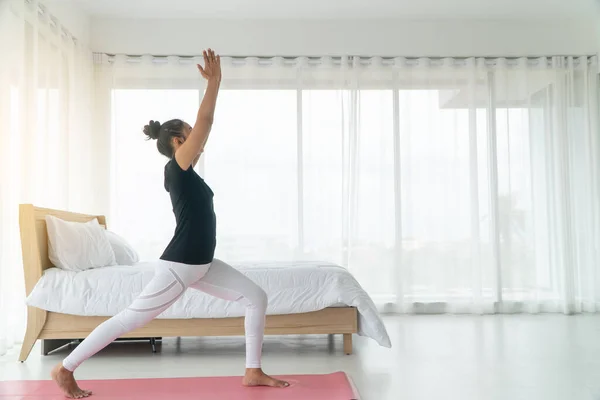 Middle aged women doing yoga easy pose to meditation with yoga in the bedroom in the morning, Concept of exercise and relaxation in the morning.