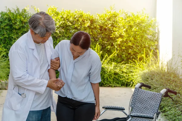 Lékař Pomáhá Zvednout Pacienta Invalidního Vozíku Při Procházce Zahradě Fyzioterapii — Stock fotografie